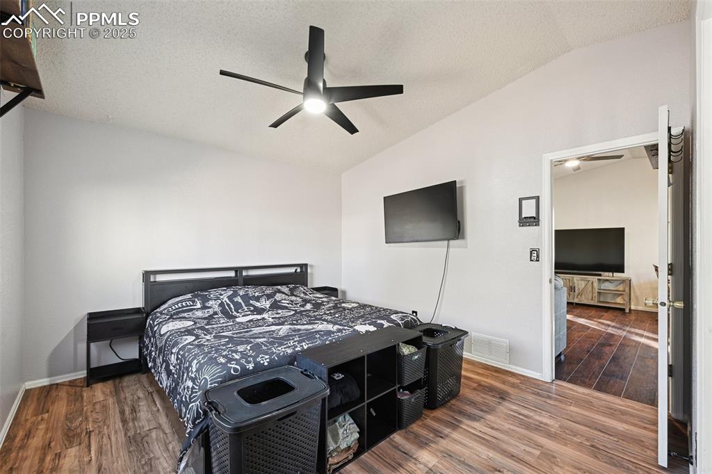 Image 17 of 23: Bedroom with, dark wood finished floors, ceiling fan, and a textured ceilin