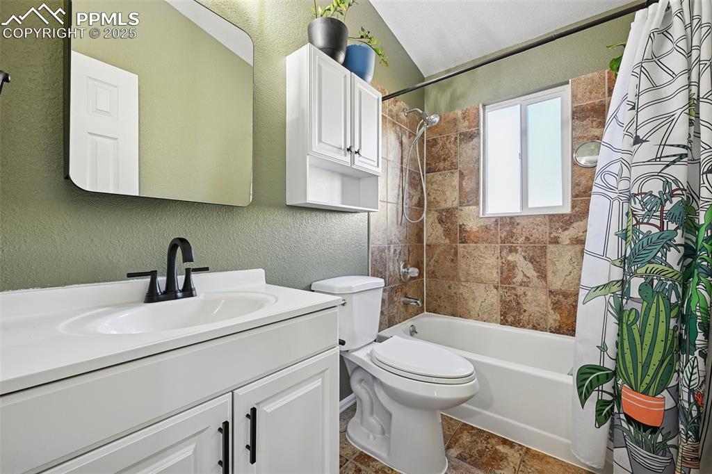 Image 18 of 23: Full bath with a textured wall, shower / bath combo with shower curtain, an
