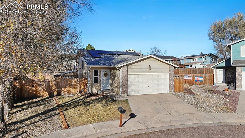 Image 2 of 23: View of front facade with roof mounted solar panels, driveway, brick siding