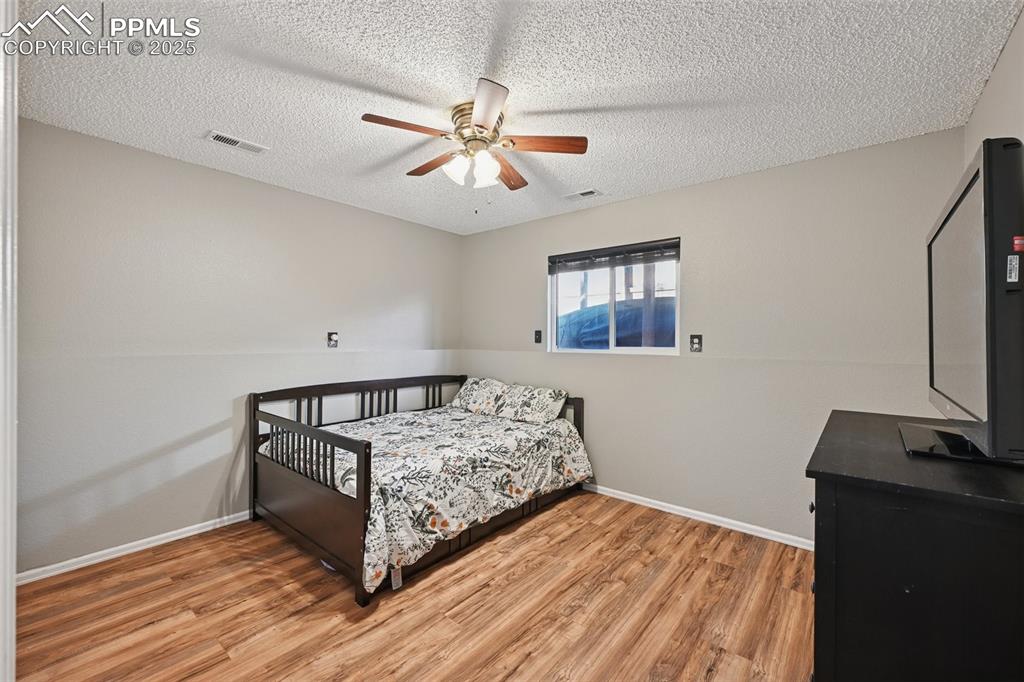 Image 21 of 23: Bedroom featuring light wood-type flooring, a ceiling fan, and a textured c
