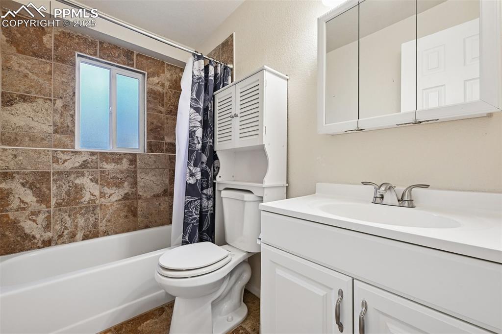 Image 23 of 23: Bathroom featuring shower / bath combination with curtain and vanity