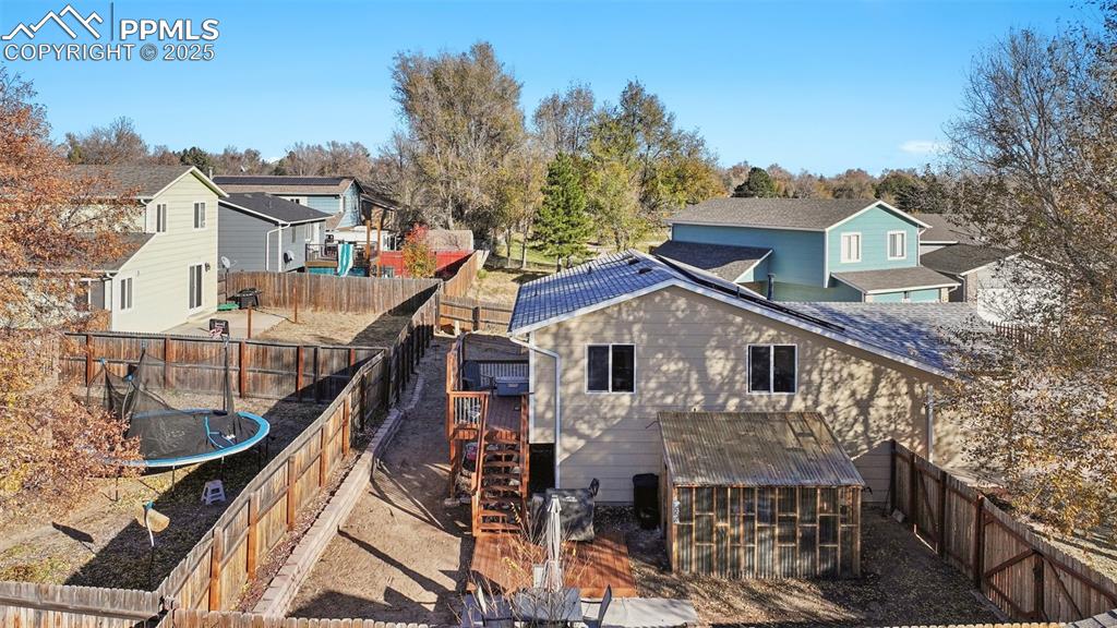 Image 7 of 23: Back of house featuring a fenced backyard, a residential view, a trampoline