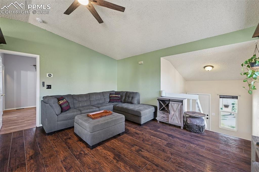 Image 8 of 23: Living area featuring a textured ceiling, dark wood-style floors, and a cei