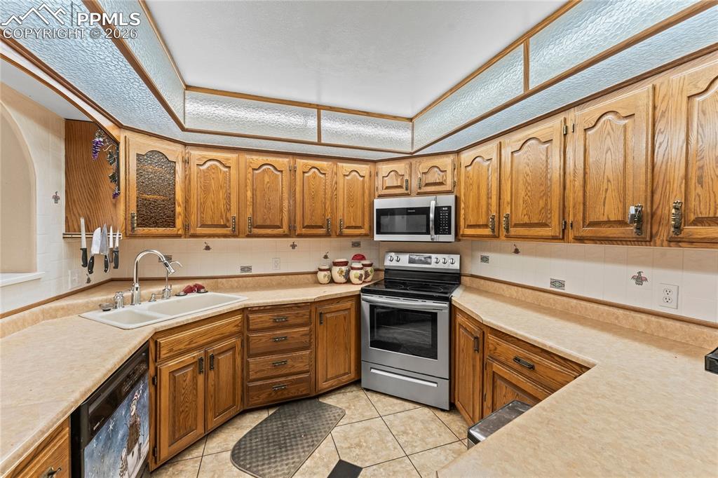 Image 10 of 41: Kitchen featuring stainless steel appliances, light countertops, light tile