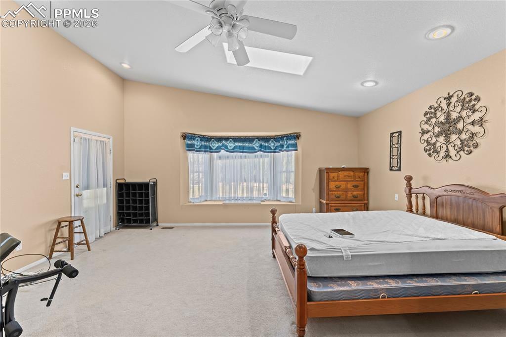 Image 17 of 41: Bedroom with vaulted ceiling, light carpet, and ceiling fan