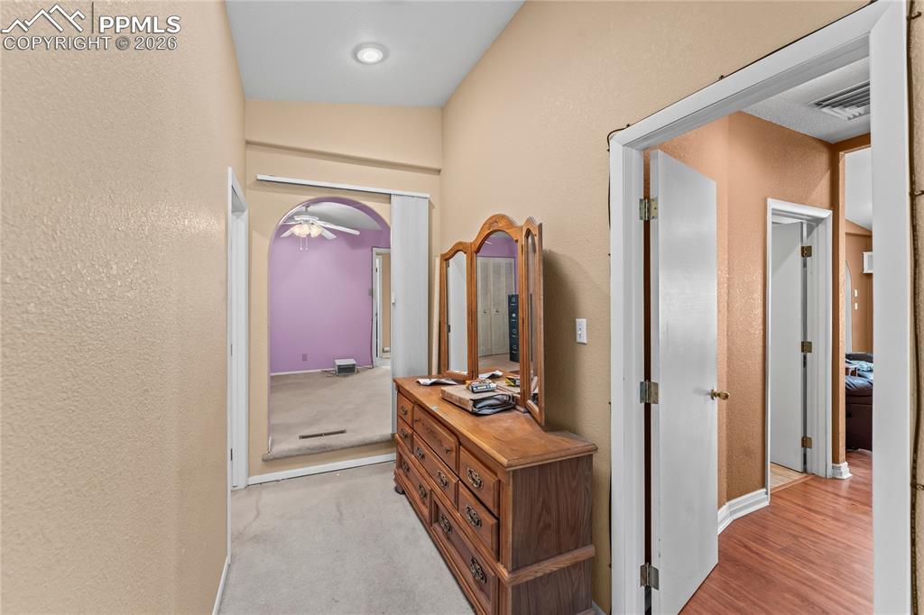 Image 19 of 41: Hall with a textured wall, light colored carpet, and arched walkways