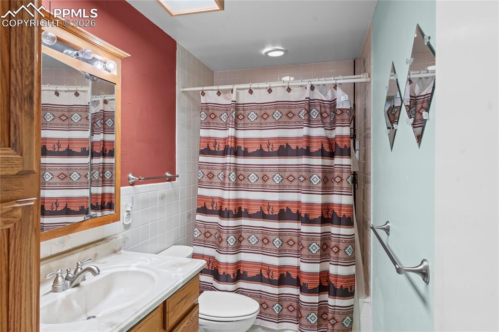 Image 22 of 41: Full bath featuring vanity, tile walls, and shower / bath combo