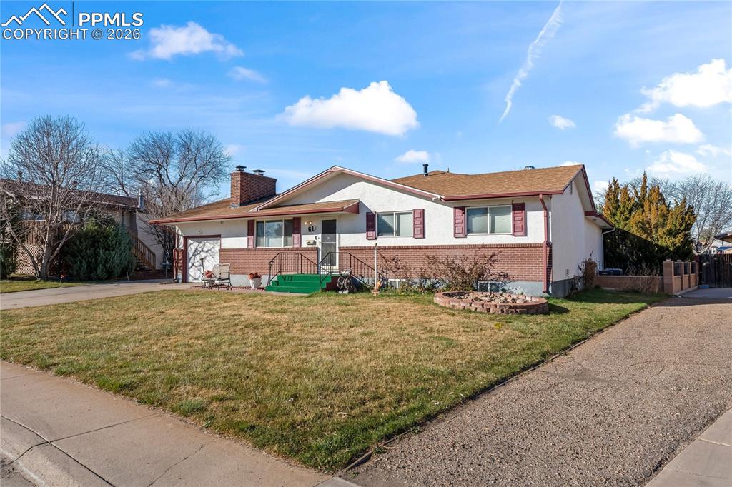 Image 3 of 41: Ranch-style house with concrete driveway, a front yard, a chimney, brick si