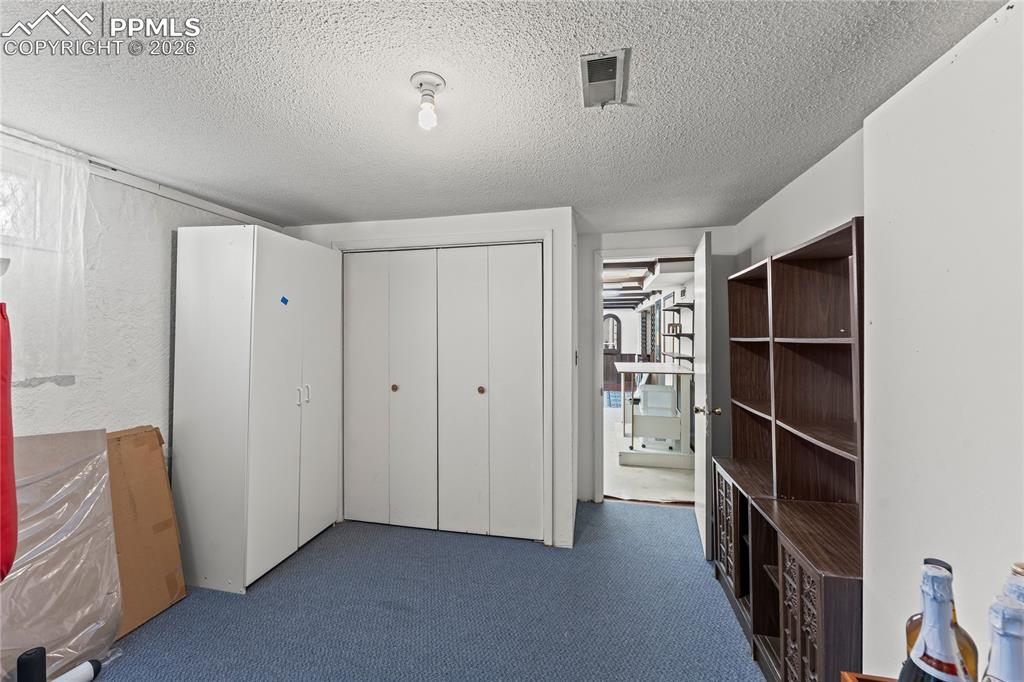 Image 33 of 41: Unfurnished bedroom with dark carpet, a textured ceiling, and a closet