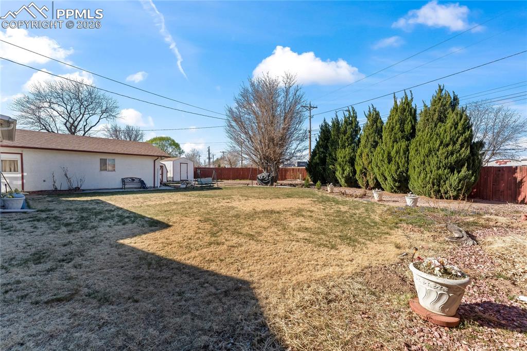 Image 36 of 41: Fenced backyard with a patio area and a storage unit