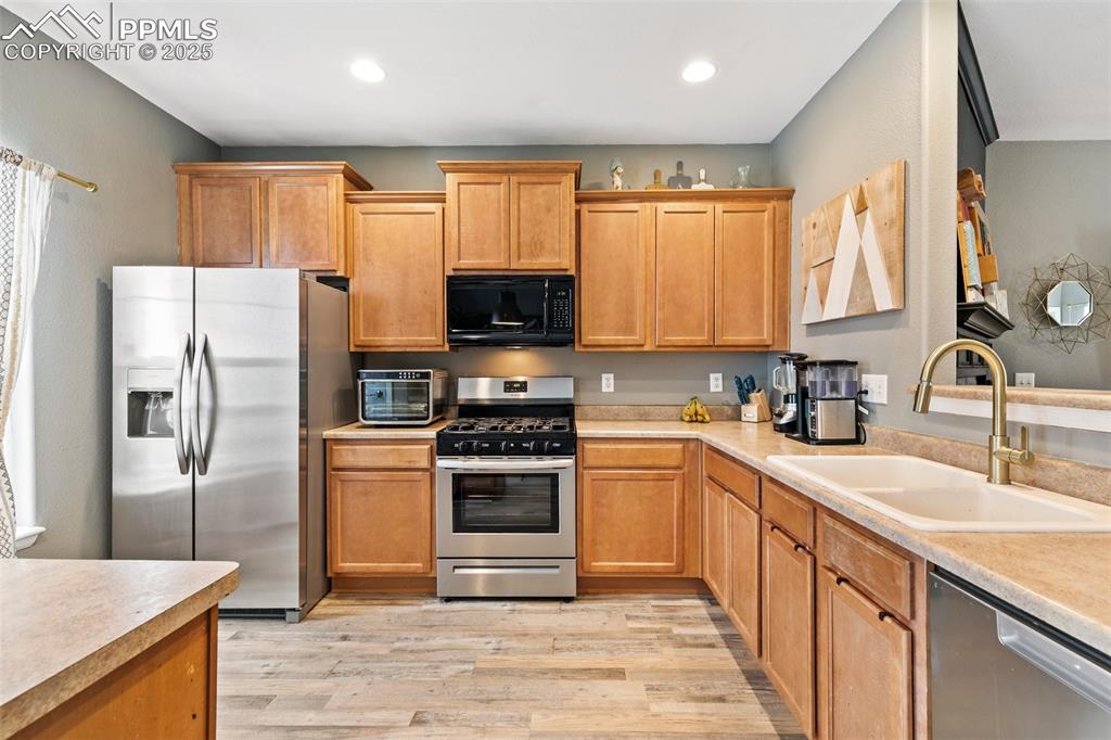 Image 14 of 34: Kitchen with stainless steel appliances, a sink, light wood-type flooring, 