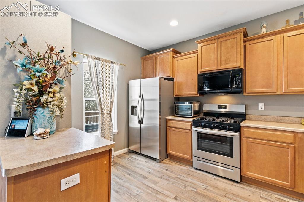 Image 15 of 34: Kitchen with stainless steel appliances, light countertops, light wood-styl