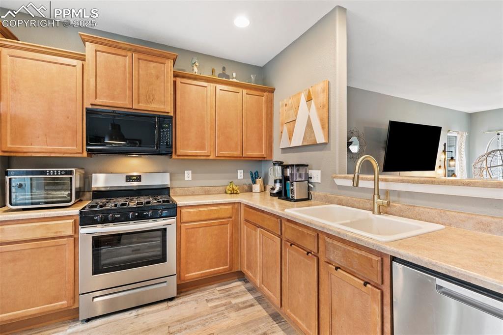Image 16 of 34: Kitchen with appliances with stainless steel finishes, a sink, light counte