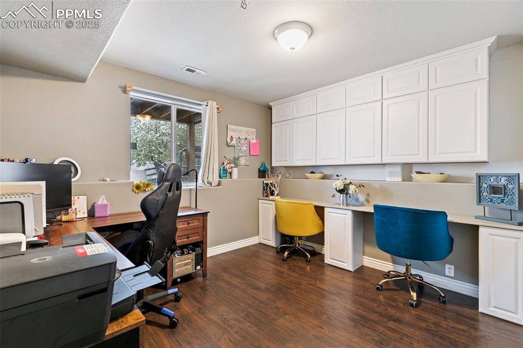 Image 19 of 34: Office space featuring dark wood-style floors and baseboards