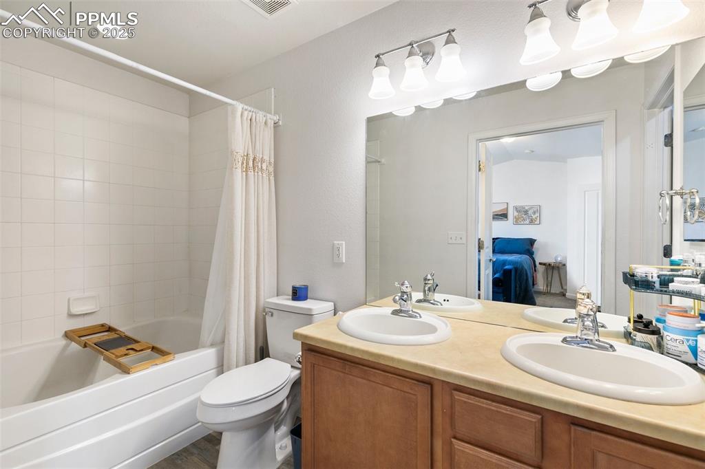 Image 24 of 34: Ensuite bathroom featuring shower / tub combo with curtain, toilet, and dou