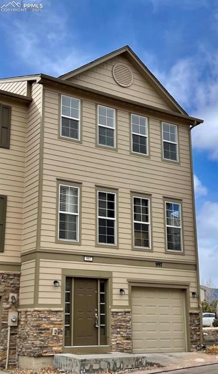 Image 34 of 34: View of property featuring stone siding and an attached garage