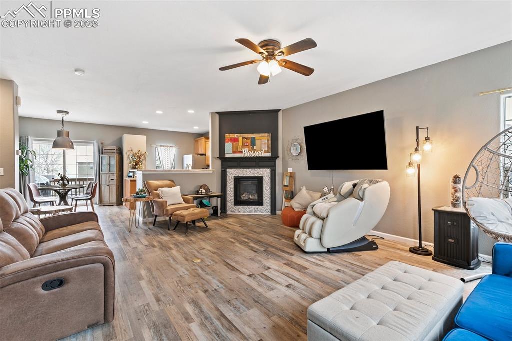 Image 8 of 34: Living area with light wood-type flooring, ceiling fan, baseboards, a glass