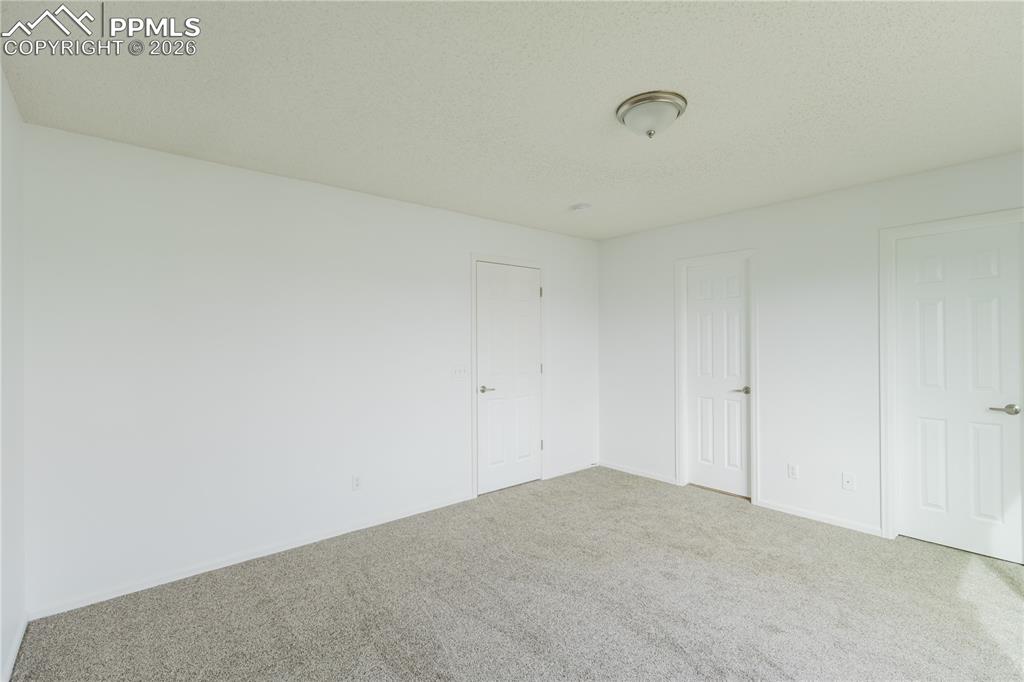 Image 20 of 42: Living area with carpeting and a view into the kitchen, featuring light woo