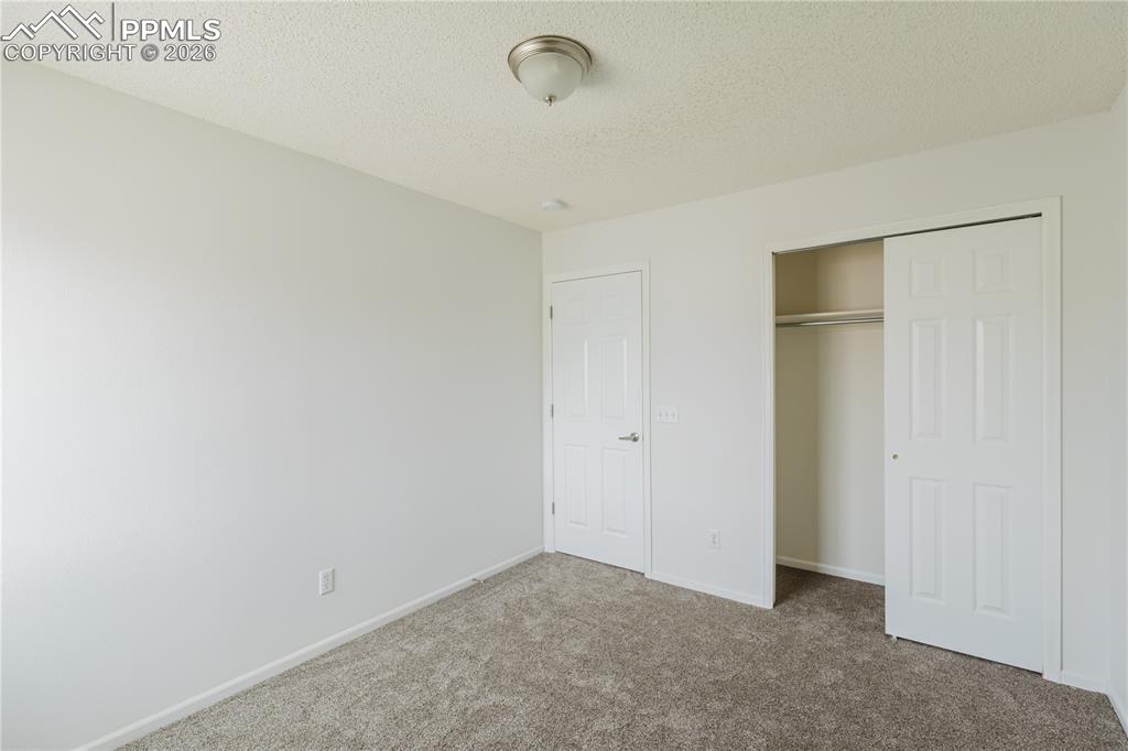 Image 26 of 42: This room features a spacious room with carpeting, white walls, and a windo