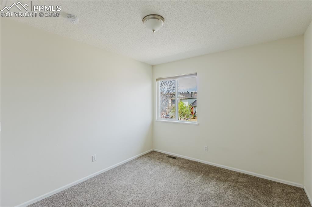 Image 30 of 42: This bedroom features white walls, neutral carpeting, a white interior door
