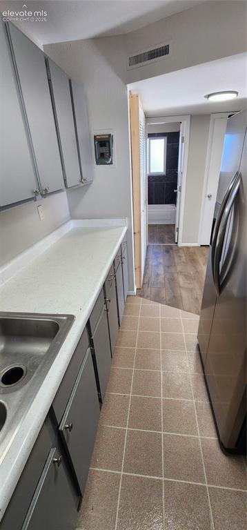 Image 15 of 18: Apt 4 - Galley kitchen with square tile flooring, stainless steel sink, lig