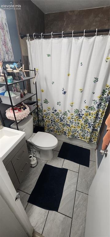 Image 9 of 18: Apt 2 - Vanity with integrated sink, toilet, and tiled flooring