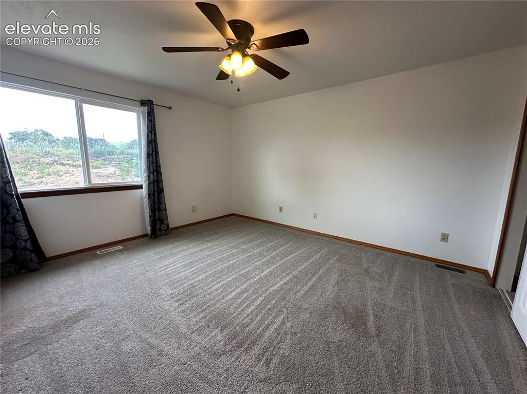 Image 13 of 15: Spacious room featuring neutral carpeting, a large window with wood trim, a