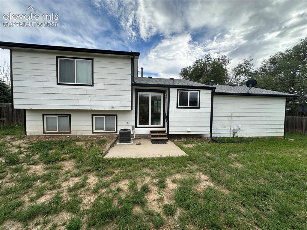 Image 15 of 15: Rear exterior featuring white siding with black trim, a sliding glass door,