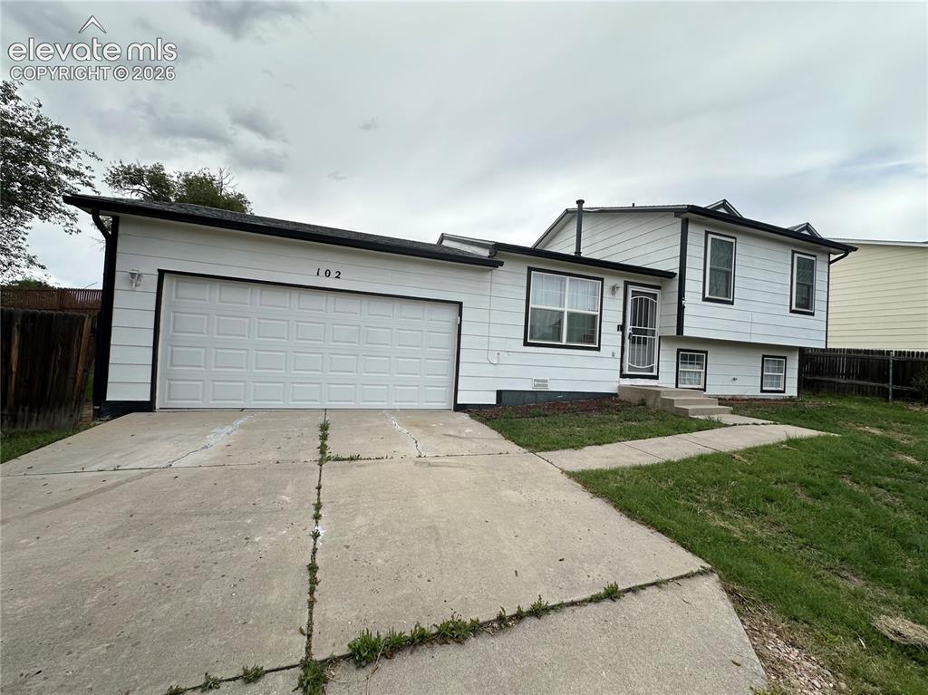 Image 2 of 15: Split-level residence featuring white siding with black trim accents and a