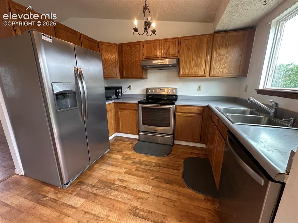 Image 5 of 15: Kitchen featuring wood-finish flooring, oak cabinetry, stainless steel appl