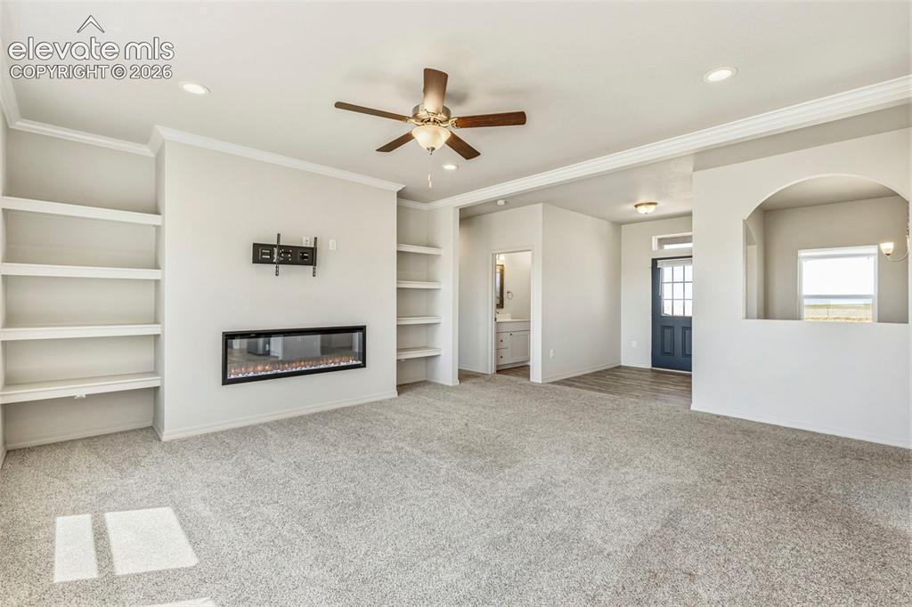 Image 10 of 38: Spacious living area featuring an electric fireplace with a wall-mounted te