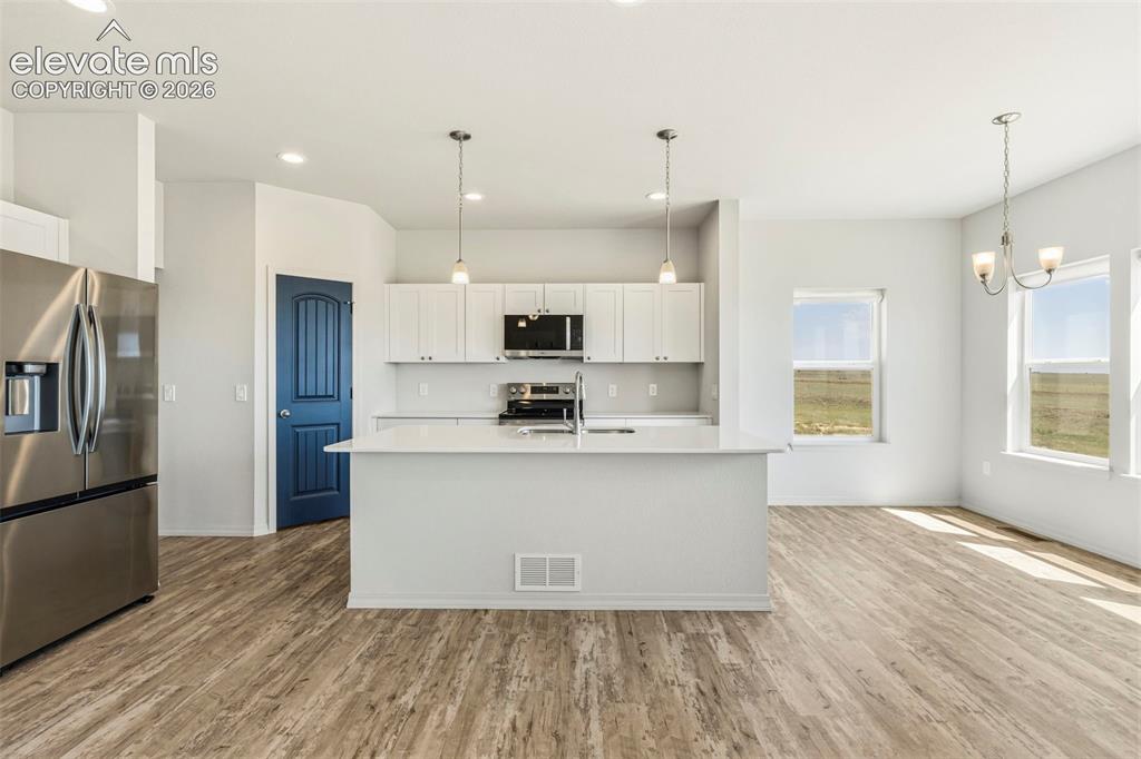 Image 13 of 38: Open-concept kitchen and dining area featuring wood-finish flooring, white