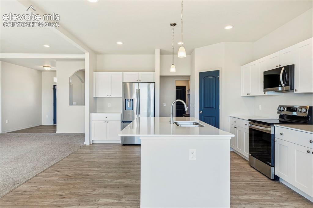 Image 14 of 38: Modern kitchen featuring white cabinetry, stainless steel appliances, a cen