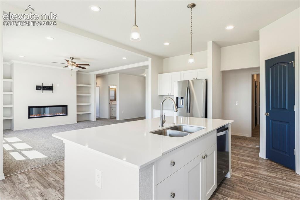 Image 15 of 38: Kitchen island with dual stainless steel sink, white cabinetry, and quartz