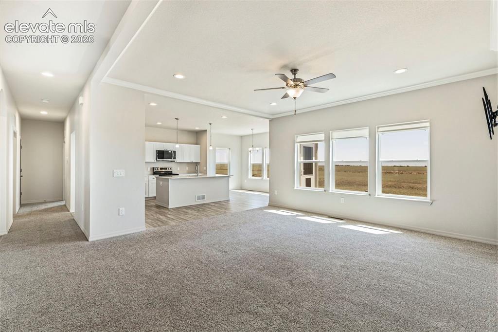 Image 17 of 38: Spacious living area featuring light gray carpeting, recessed lighting, and