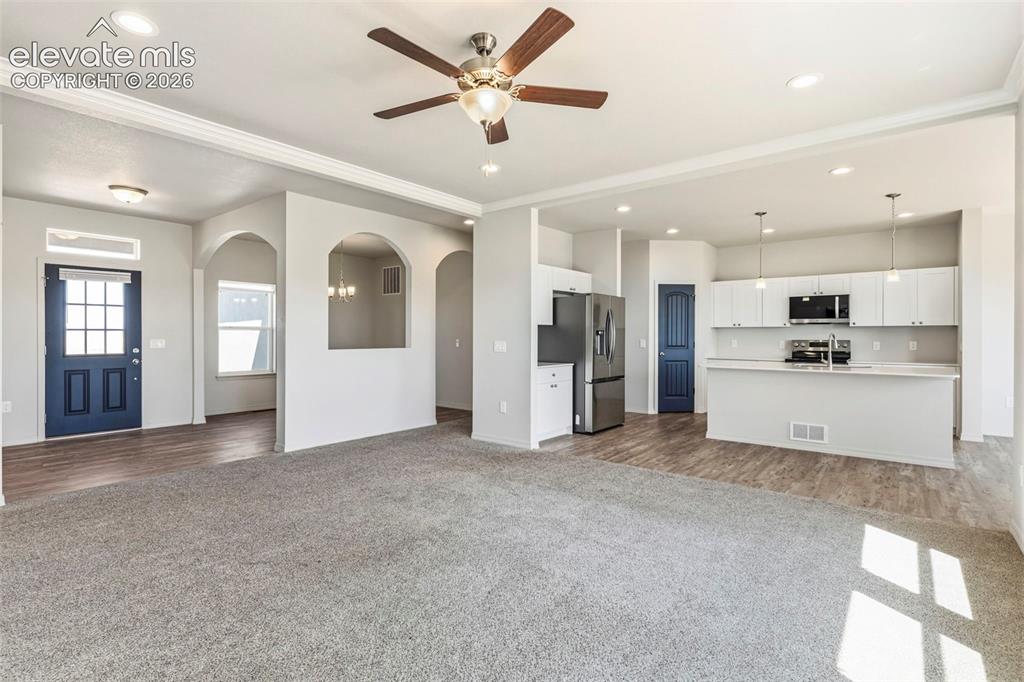 Image 18 of 38: Expansive open concept living area featuring a ceiling fan with light fixtu