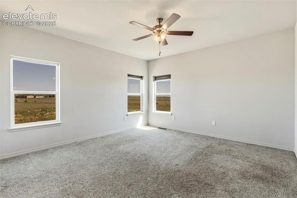 Image 20 of 38: Spacious room featuring light gray carpeting, multiple windows providing na