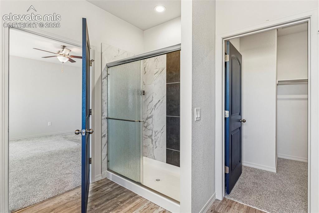 Image 24 of 38: Walk-in shower featuring patterned tile surround and clear glass enclosure