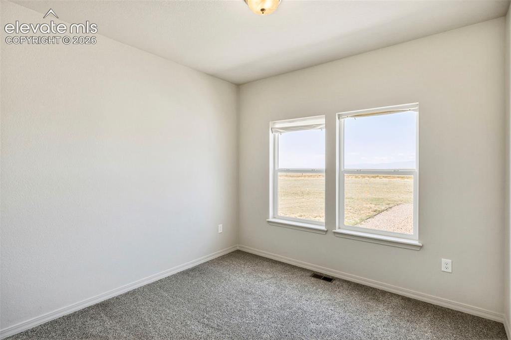 Image 26 of 38: Neutral-toned room with light gray walls and plush gray carpeting