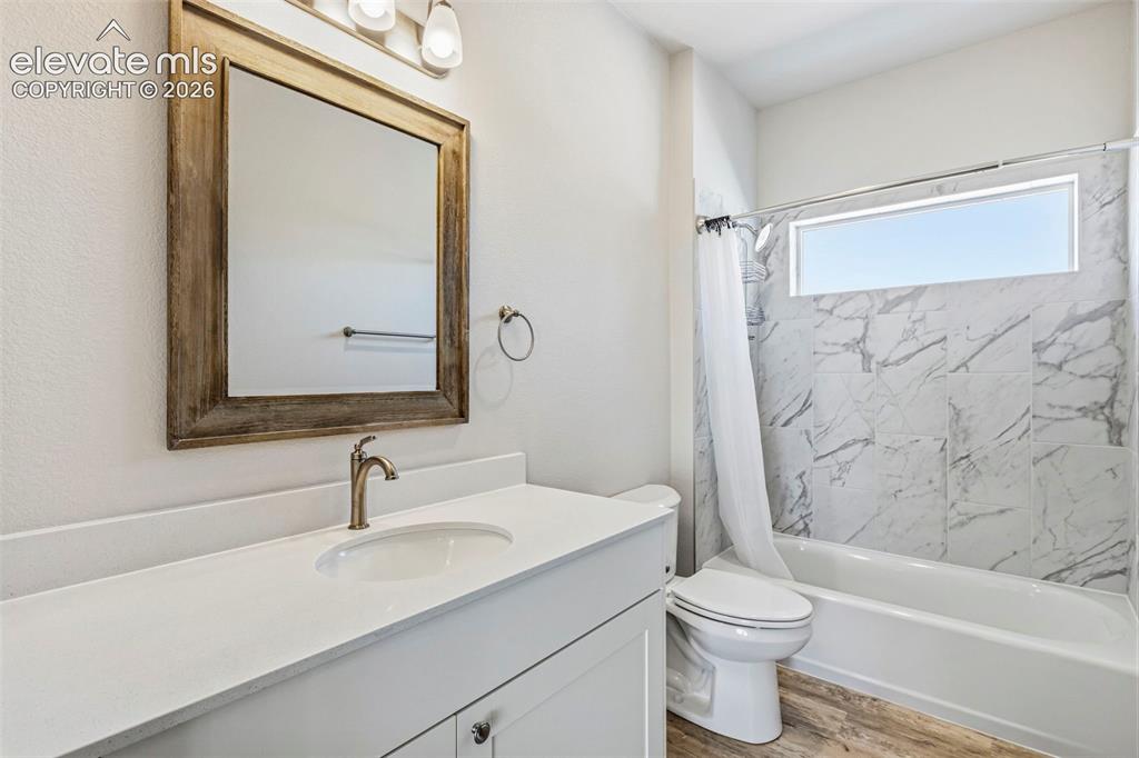 Image 27 of 38: Bathroom featuring a white vanity with an integrated sink, brushed bronze f