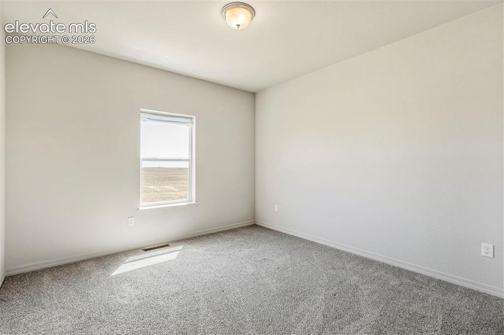 Image 28 of 38: Neutral-toned room featuring a single window and gray carpeting