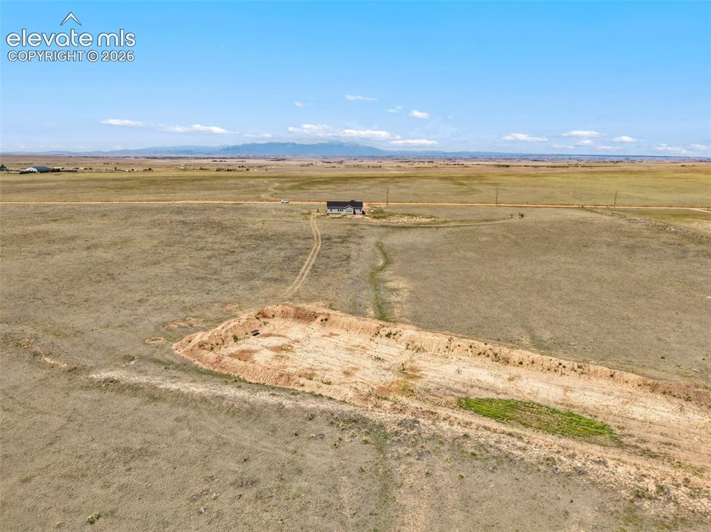 Image 36 of 38: Expansive land parcel featuring a distant single-family residence, a cleare