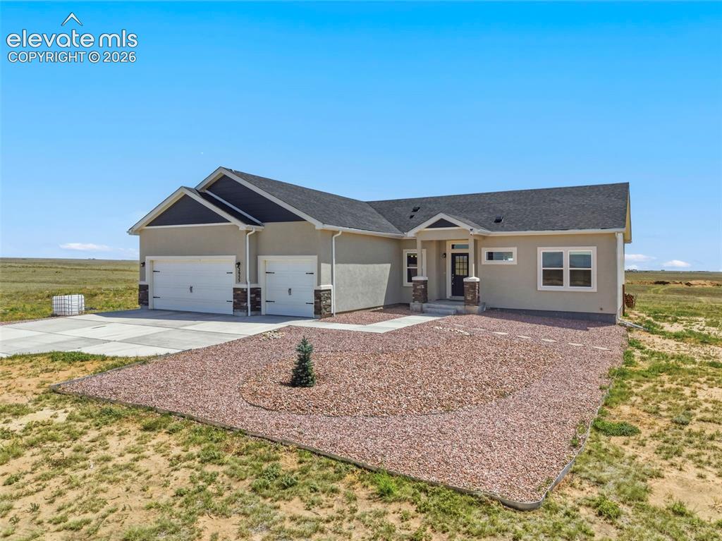 Image 5 of 38: Contemporary ranch-style residence featuring a stucco exterior, dark shingl