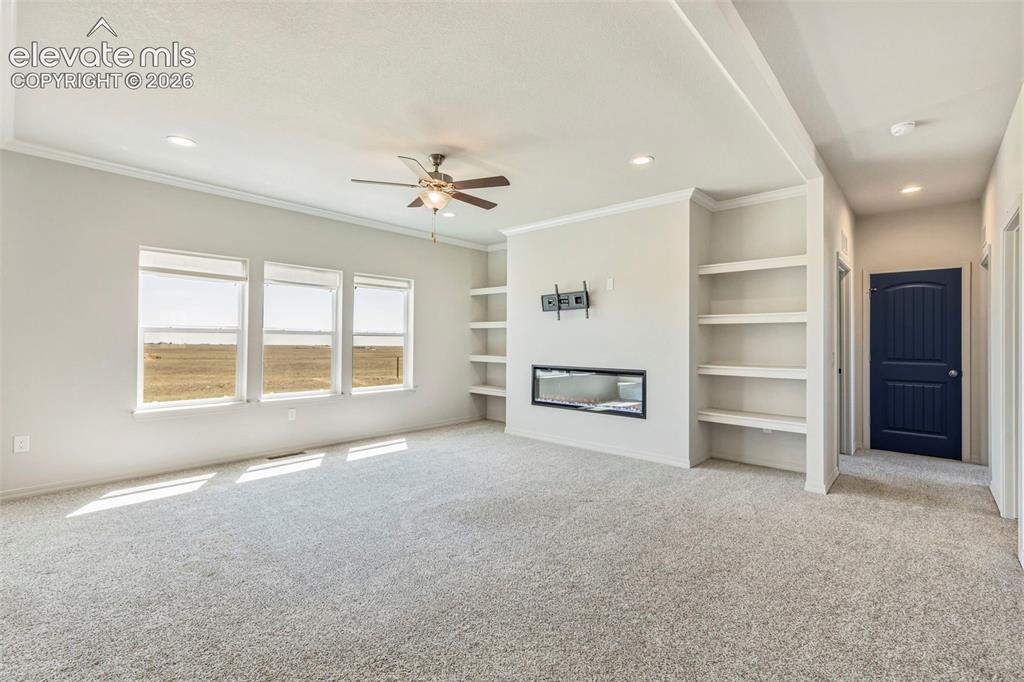 Image 9 of 38: Bright living space featuring a built-in linear fireplace, custom shelving,