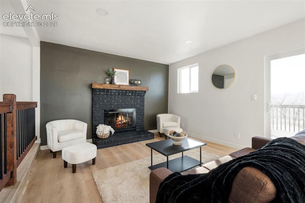 Image 16 of 50: Living area featuring a black brick fireplace with a wood mantel, light woo