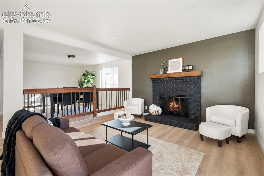 Image 17 of 50: Living area featuring a black brick fireplace with a wood mantel, light woo
