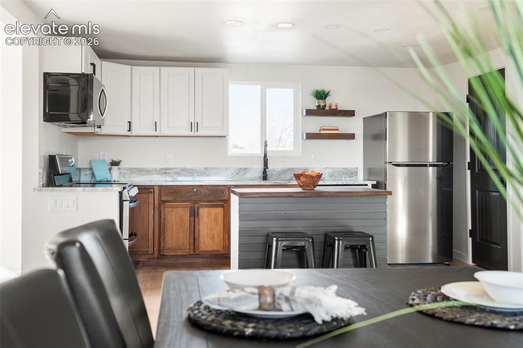Image 21 of 50: Kitchen featuring white upper cabinetry, natural wood-finish lower cabinetr