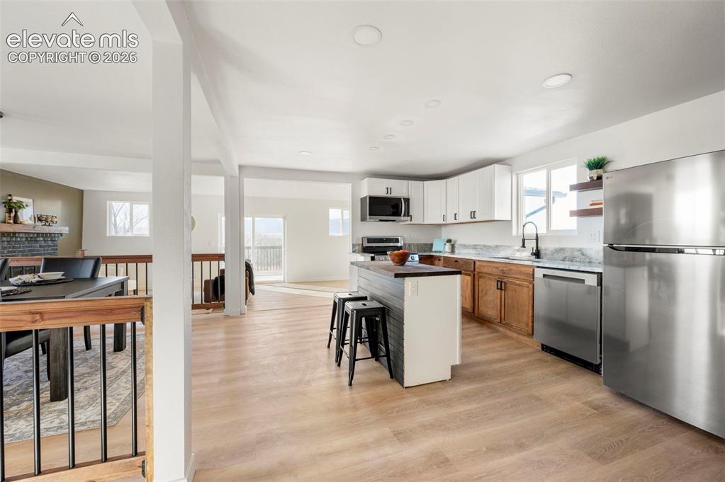 Image 23 of 50: Modern kitchen featuring light wood-finish flooring and a central island wi