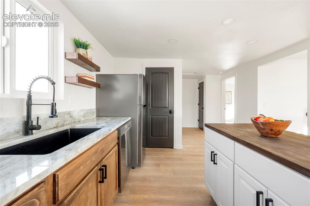 Image 25 of 50: Kitchen featuring light wood-finish flooring, white walls, and recessed lig