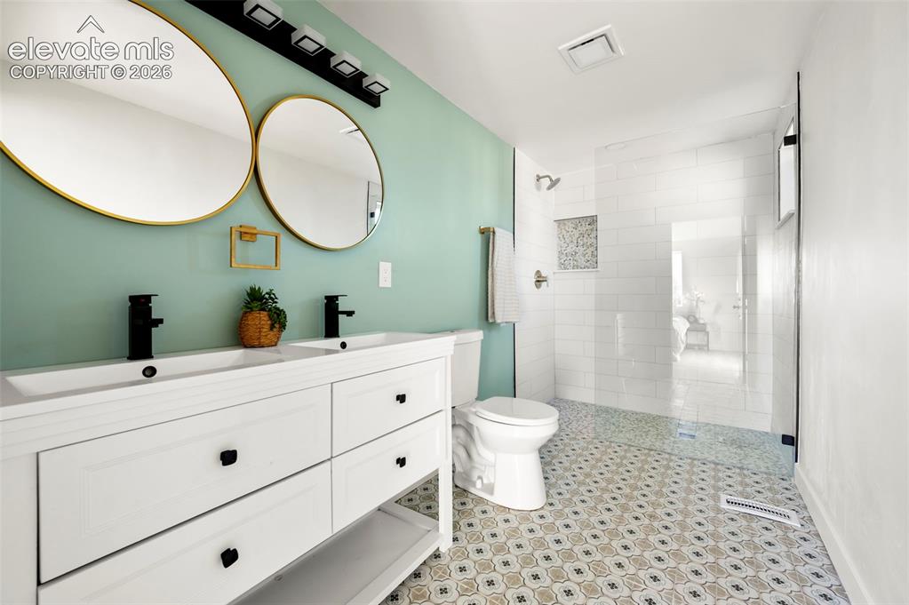 Image 28 of 50: Bathroom featuring a double vanity with integrated sinks, black fixtures, a